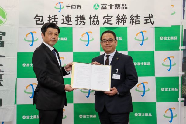 株式会社富士薬品 配置事業本部配置営業統括部営業部 伊庭部長と小川市長が2人で協定書を持って正面を向いている写真
