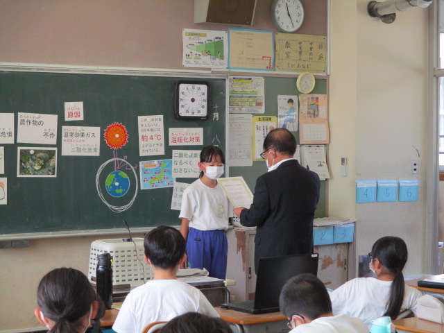 千曲市地球温暖化対策協議会長から委嘱状を手渡される女子児童の写真