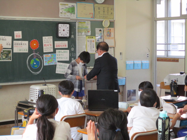 千曲市地球温暖化対策協議会長から委嘱状を手渡される男子児童の写真