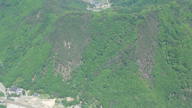 緑で覆われた山肌が2ヶ所部分的に茶色になっている写真