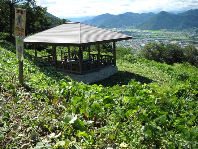 小高い草はらの中にある屋根のついた木造の休憩所の写真