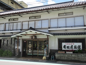 「有田屋旅館」と書かれた看板がある、2階建ての旅館の外観の写真