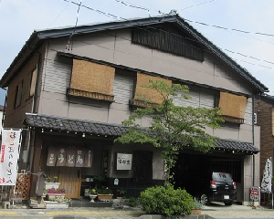うどんと書かれた暖簾がかかっている、瓦屋根のある大きな建物の写真
