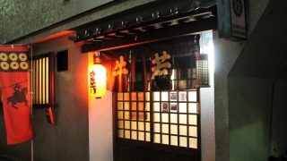 牛若と書かれたのれんがかかり、横にやきとりと書かれた提灯が光っている、お店の入り口の写真