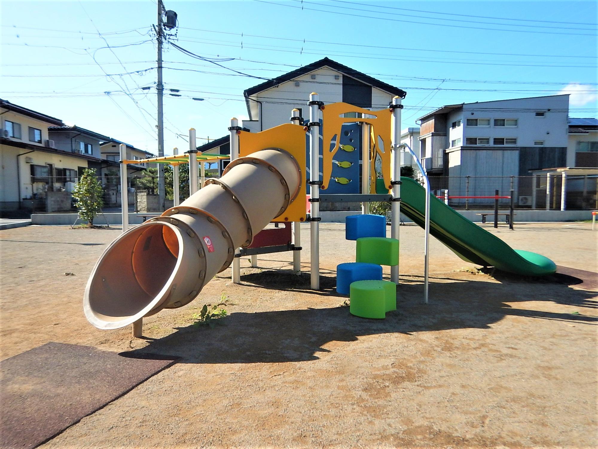 筒状の滑り台と緑色の滑り台が合体した複合遊具の写真