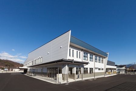 青空と白い壁面の施設外観を映した千曲市第1学校給食センターの写真
