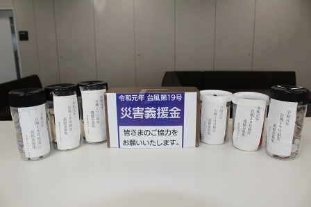 皆様のご協力をお願いします。と書かれた張り紙と義援金の入ったボトルが並んでいる写真