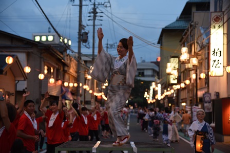 温泉街の道路で踊りを踊る女性たちの写真