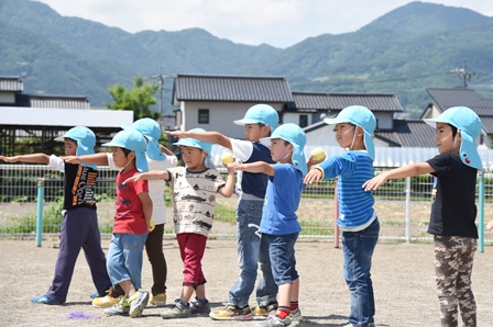 横に並びボールを振りかぶるポーズをとる園児達の写真
