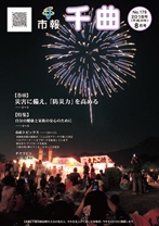 夜空に満開の花火が打ちあがっている様子を、観客が見ている2018年8月号の市報表紙