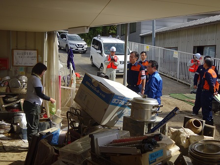 日用品などが乱雑に積み重なっている倉庫のような場所を映した写真