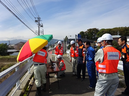 作業スタッフたちが川沿いの状況を調べている写真