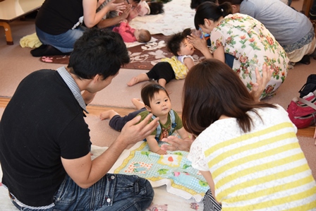 赤ちゃんと身振り手振りでコミュニケーションをとる親達の写真
