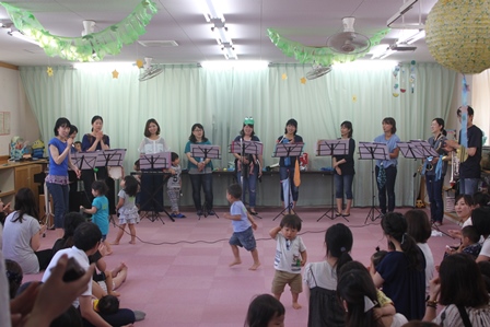 親子の前で演奏を披露するママバンドの写真