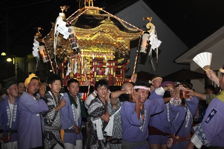 華やかな金色の神輿とそれを担ぐ男たちの写真