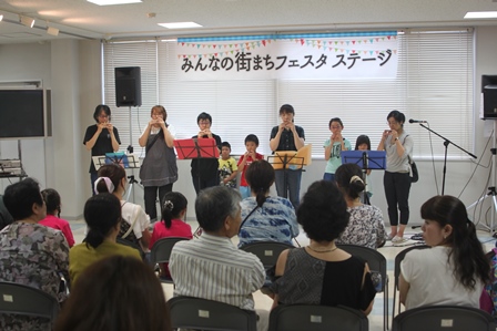 楽器の演奏をする子供と大人とそれを鑑賞する人々の写真
