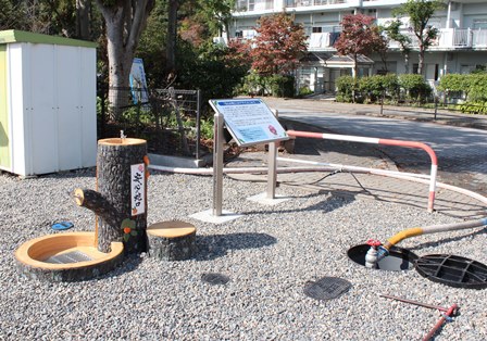 水飲み場がある広場の端のマンホールから水を引いている写真