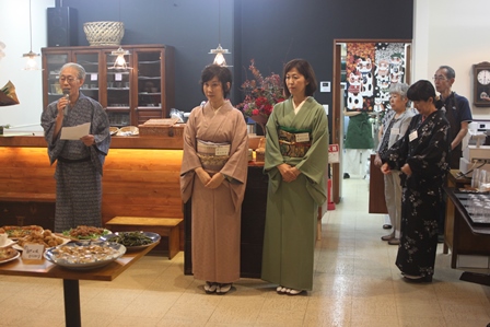 新しくオープンするカフェのお披露目の会で着物を着た従業員がスピーチをしている写真