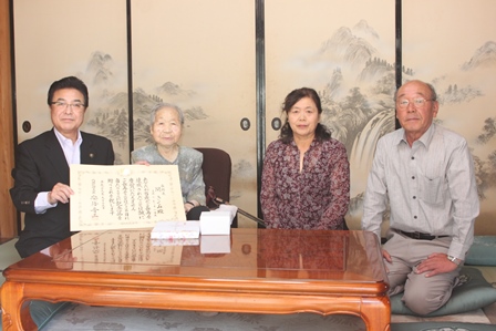 賞状を持った市長と100歳を迎えたおばあさんが和室でおばあさんの家族と一緒の写真