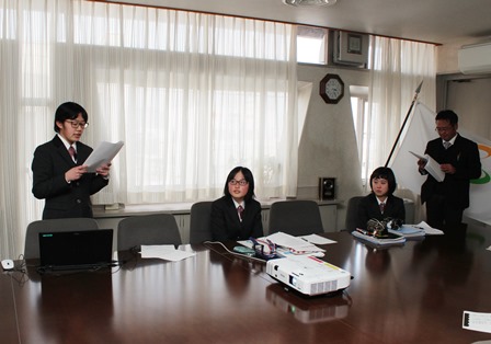 庁舎の会議室の大きなテーブルに間をあけて座ったり立って発言したりしている3人の中学生の写真
