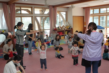 職員といっしょに手遊び歌を楽しむ親子の写真