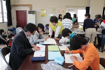 子どもたちの勉強会に大人も混ざって勉強を教えている写真