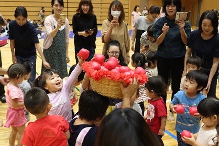 バスケットに入った赤い玉を取り合っている幼児たちの写真