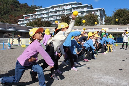 園児たちが園庭で元気よくボールを投げている写真
