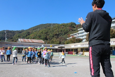 先生がボール投げをしている園児たちの指導をしている写真