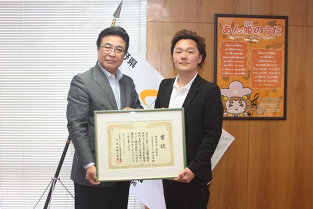 受賞した会社職員と一緒に表彰をもって記念写真を撮る市長の写真