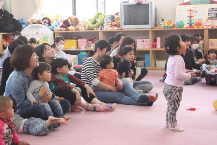 親に抱っこされながら催し物を見る子供たちの写真