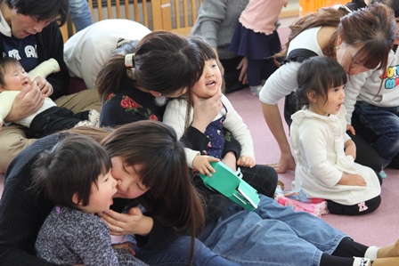 自分の子供を膝に乗せ、口のチェックをする親子たちの写真