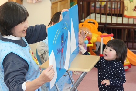 小さな子の前で紙芝居をしている女性の写真