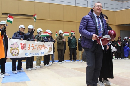 国旗の手機と横断幕を手にハンガリーからきた理事を歓迎している写真