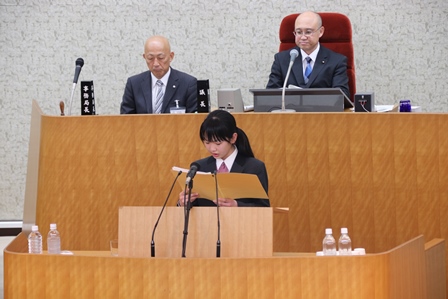 中学の女子生徒が議場の台に上り発表をしている写真