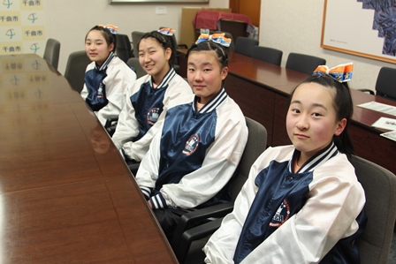 机の前に座って目線をこちらに笑顔の女の子4人の写真