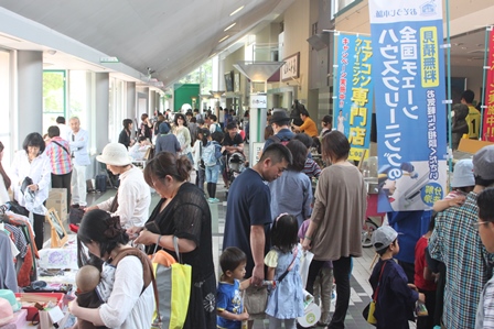 会場の出展ブースが並ぶところで賑わう人々の写真
