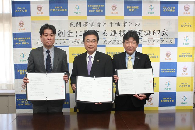 保険サービス会社2社の男性スタッフと記念写真を撮る市長の写真