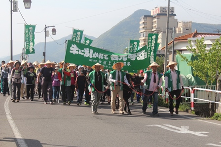 緑の幟を持ち戸倉上山田温泉から善光寺まで歩く大勢の参加者の写真