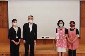 プロジェクターの横に並んで立っている関係者一同の写真