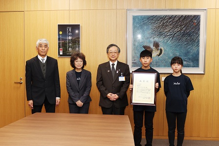 室内でカメラのほうを向き並んで記念撮影をしている関係者一同の写真