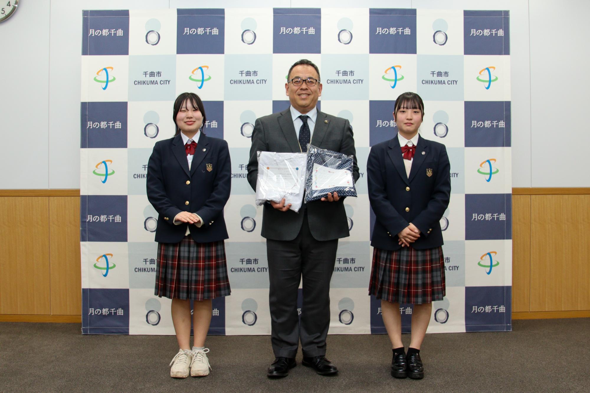 楽らくねまきを寄贈され記念撮影をする小川市長(中央)と山崎さん(右)と渋沢さん(左)