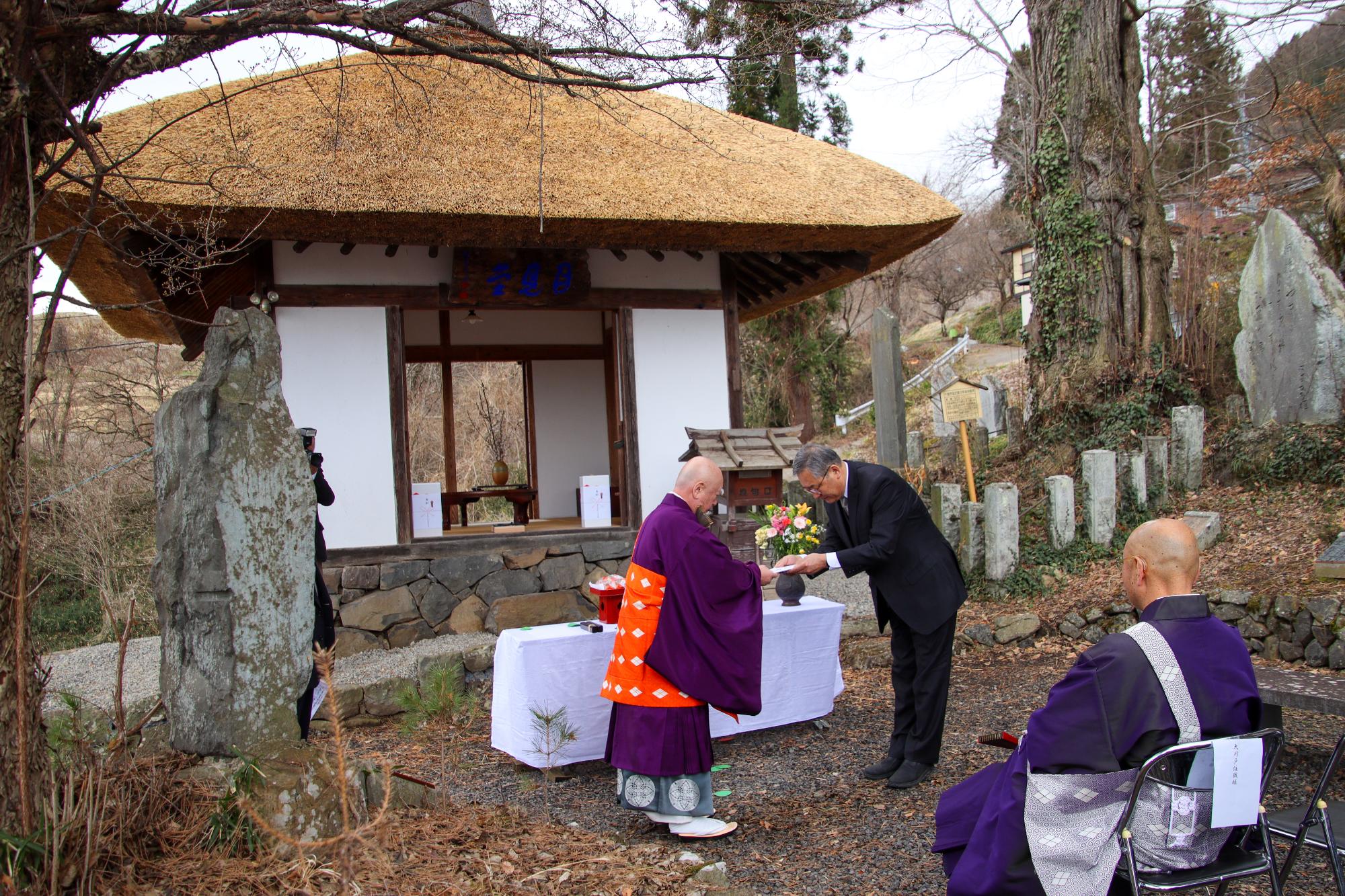 クラウドファンディングで集まった寄付金の目録を若林会長(右)から大沢住職(左)に贈呈している様子