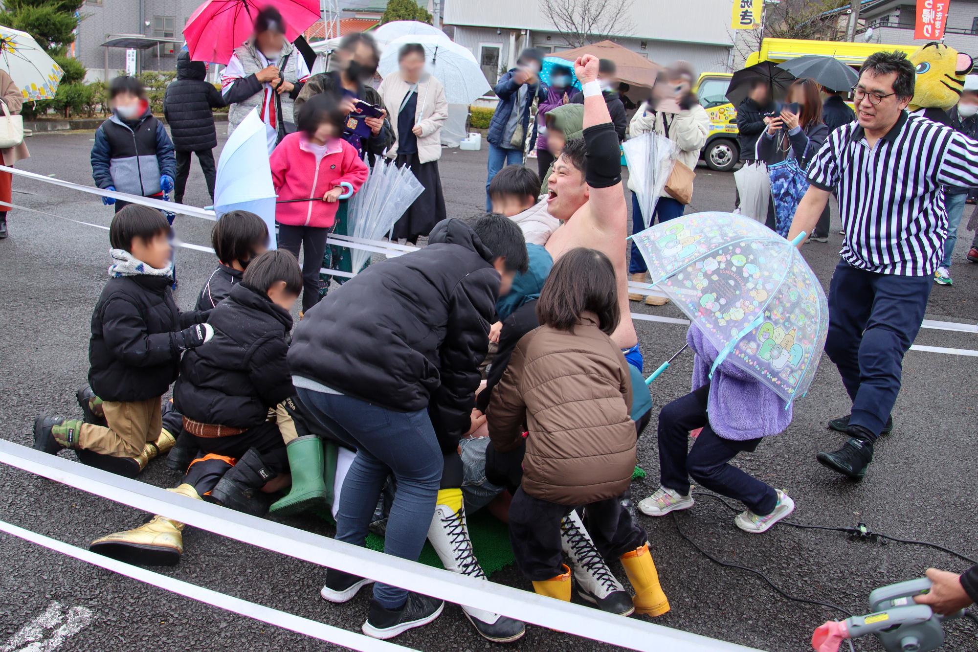 信州プロレスの試合中、最後に観客の子どもたちをリングの中に呼び、寝転んだ選手を押さえて3カウントをとっている様子