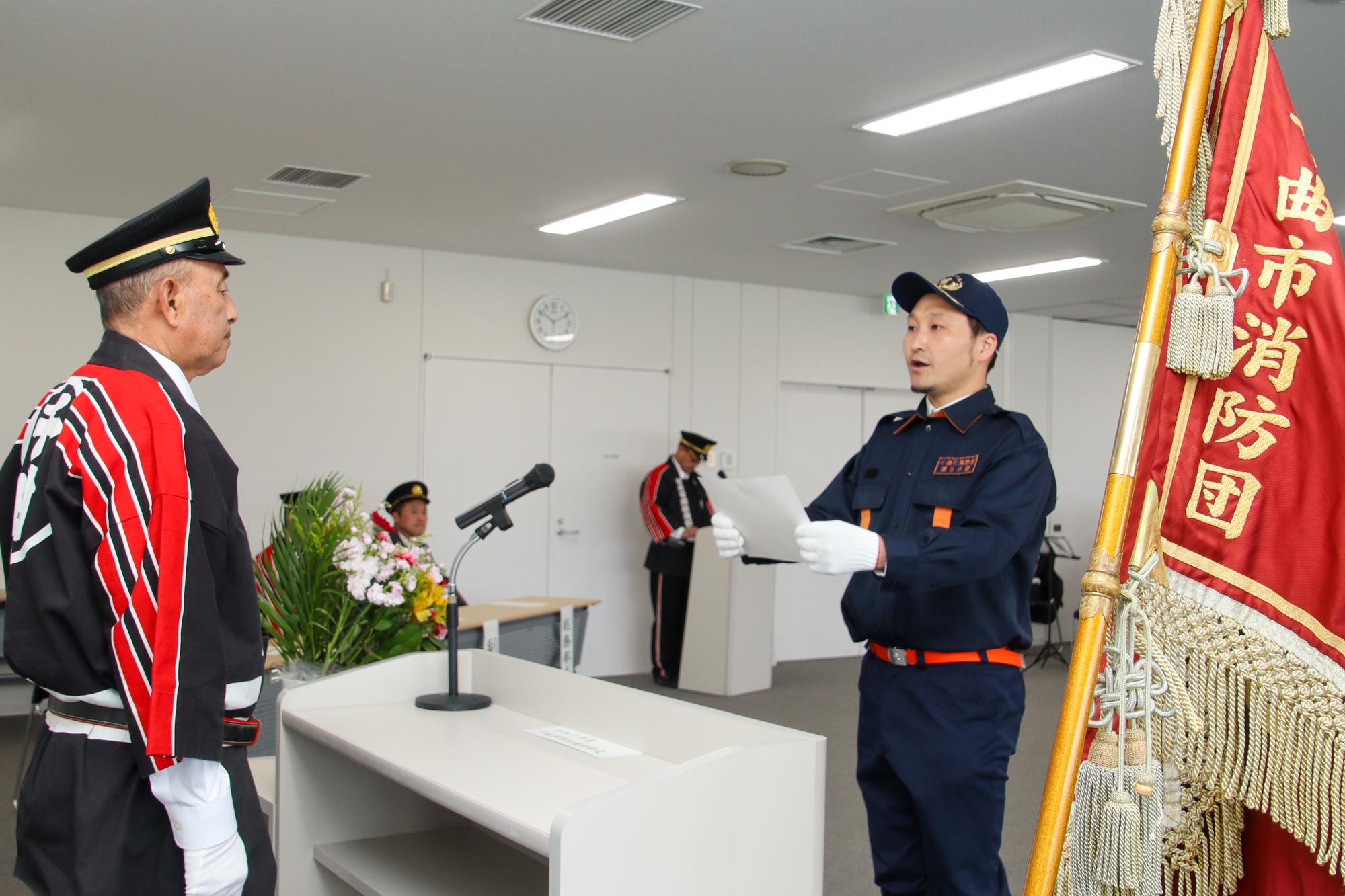 瀬在消防団長(左)に宣誓を行なう消防団員の碓田さん