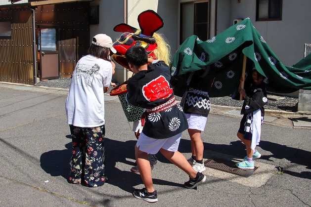 健康を願い赤ちゃんの頭にやさしく噛みつく子ども獅子