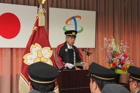 壇上で話をする、警察帽を被った臼井団長とそれを聞く団員達の写真