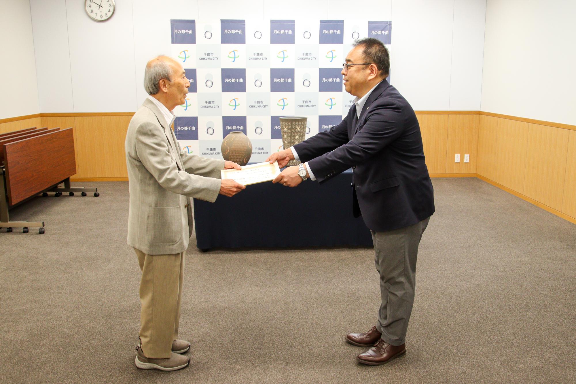 寄贈作品の前で、感謝状を贈呈する小川市長(右)とそれを受け取る小林さん(左)