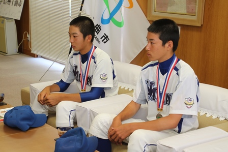 メダルを首から下げた男性選手が椅子に座っている写真