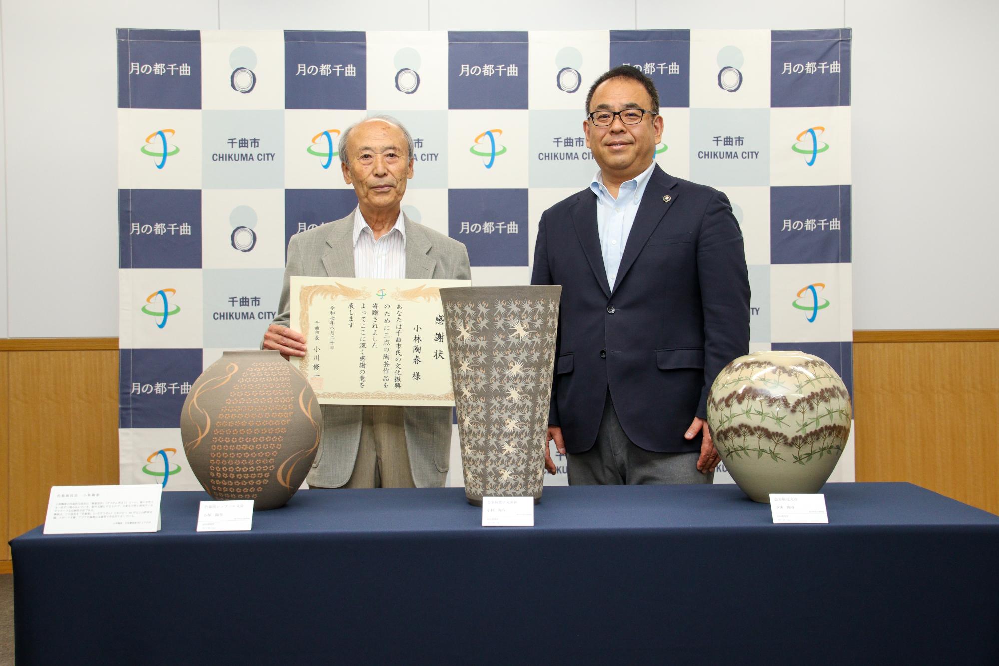寄贈された作品を前に記念撮影をする小川市長(右)と小林さん(左)